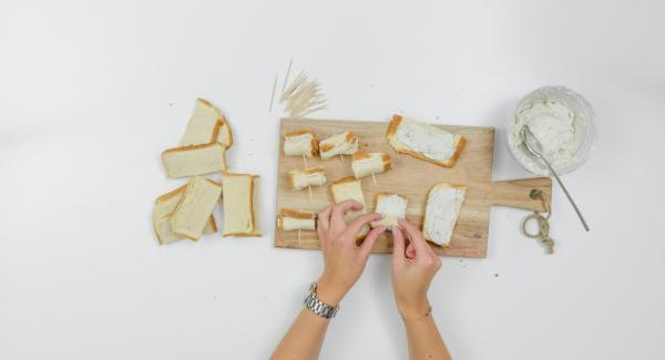 Spalmare un po’ di crema al formaggio su ciascuna striscia di pane, arrotolare e fissare con degli stuzzicadenti.