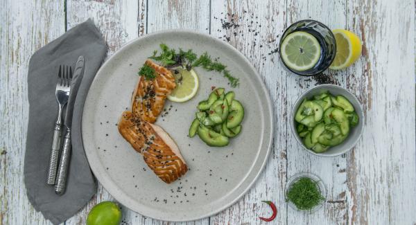 Tritare finemente le foglie di aneto. Insaporire i filetti di salmone con sale e pepe, servirli con l’insalata di cetriolo e peperoncino e cospargerli con l’aneto e il sesamo.