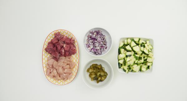 Tagliare il pollo e la bistecca di manzo a dadini di 1-2 cm. Pelare la cipolla, pulire le zucchine e tagliare entrambe a dadini. Fare altrettanto con i cetriolini.