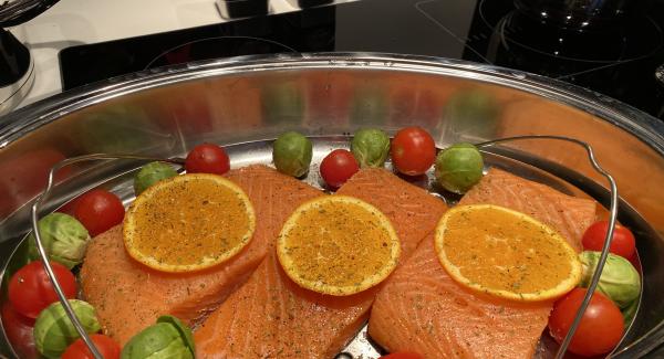 Adagiare le fette di salmone aggiungere i pomodorini e i cavoli di Bruxelles. Mettere sopra al salmone le fette di arancia e distribuire a piacere le spezie AMC